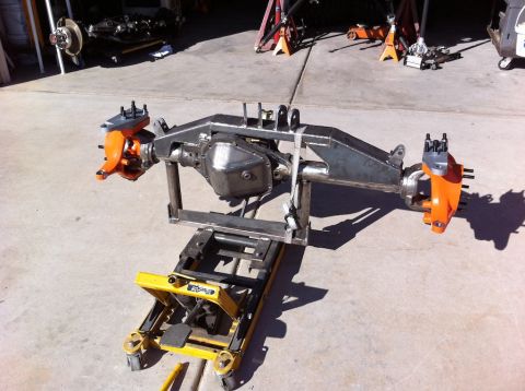 Suzuki Samurai - A custom front axle assembly, orange brake calipers, is shown mounted on a yellow jack.