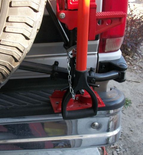 1996 Ford Bronco - Hi-lift jack mounted on the rear of a vehicle, next to the spare tire.