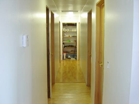 1984 Ford Mustang - A view down a residential hallway, showing doors on either side and a well-stocked storage closet at the far end.