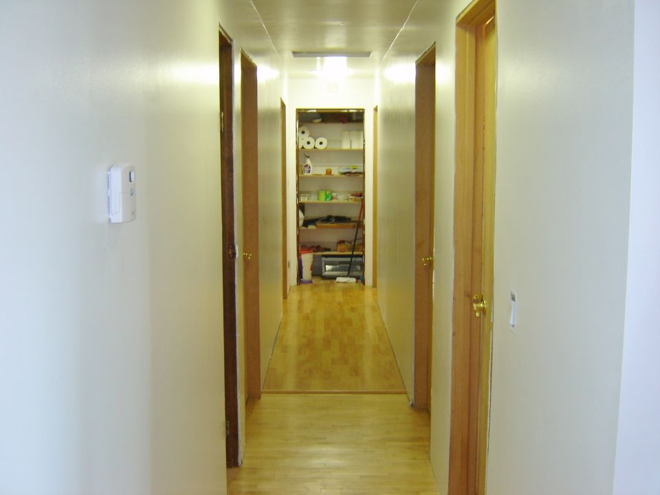 Interior hallway with multiple doors and a storage closet at the end