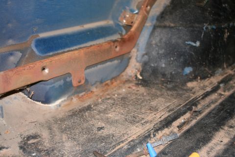 1989 Ford Bronco - Interior floor shows rust and dirt, with a metal bracket attached.