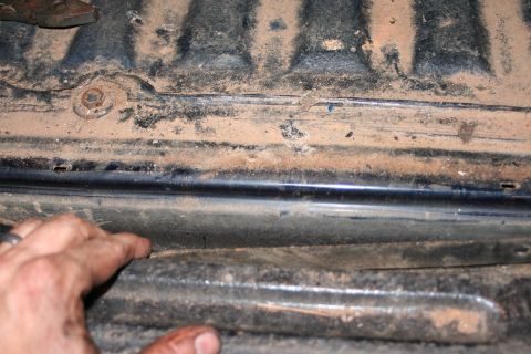 1989 Ford Bronco - Close-up of a dirty vehicle frame rail, showing rust and dirt accumulation.