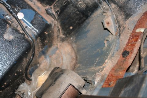 1989 Ford Bronco - Close-up of a dirty and rusted vehicle interior, focusing on structural components and a seatbelt.