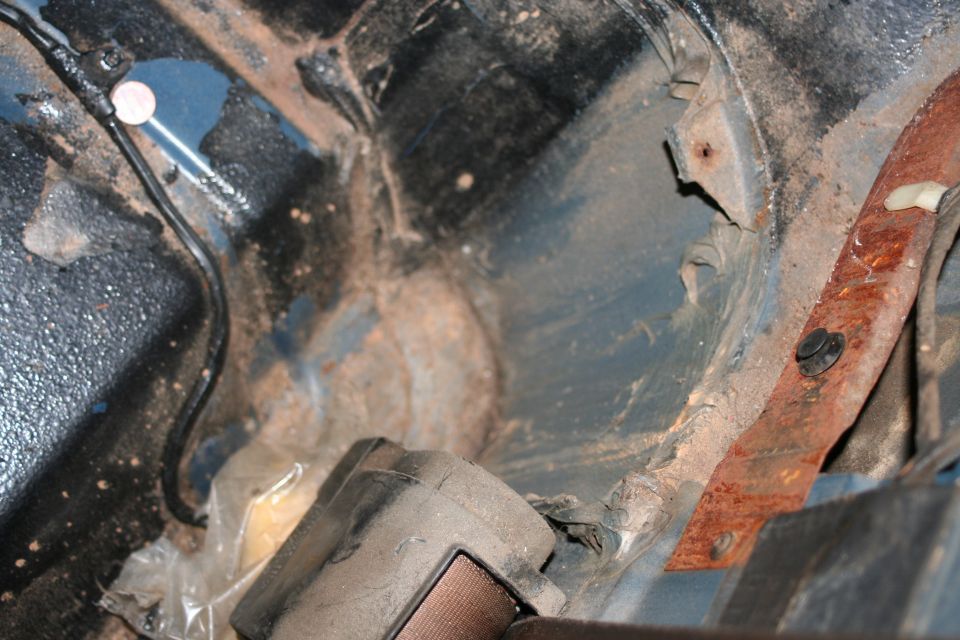 Blue vehicle interior showing rust and dirt on metal components and a seatbelt buckle