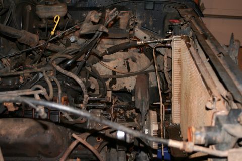 1989 Ford Bronco - The engine bay is cluttered with hoses and mechanical parts, with the radiator prominently visible.
