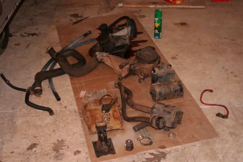 1989 Ford Bronco - Engine components and hoses are spread out on a cardboard sheet on the floor.