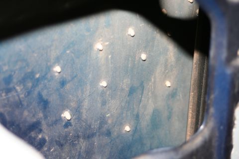 1989 Ford Bronco - Close-up of a blue panel with multiple white rivets, possibly from a vehicle's interior or undercarriage.