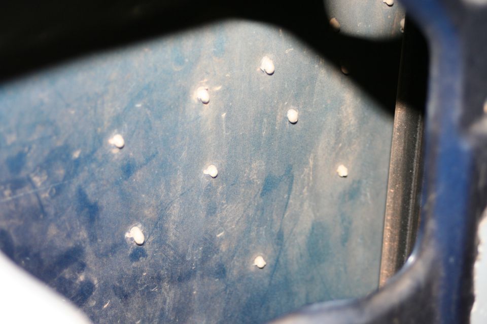Blue metal panel with scattered white rivets and a dark vertical edge