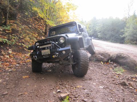 2008 Jeep Wrangler - A black Jeep Wrangler navigates a rocky trail with fall foliage in the background.