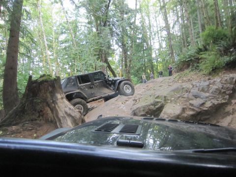 2008 Jeep Wrangler - Two Jeeps navigate a challenging, rocky off-road trail through a dense forest.