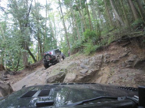 2008 Jeep Wrangler - Two Jeeps navigate a challenging rocky trail in a wooded area.