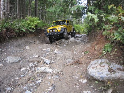 2008 Jeep Wrangler - A yellow Jeep Wrangler tackles a challenging off-road path with steep inclines and obstacles.