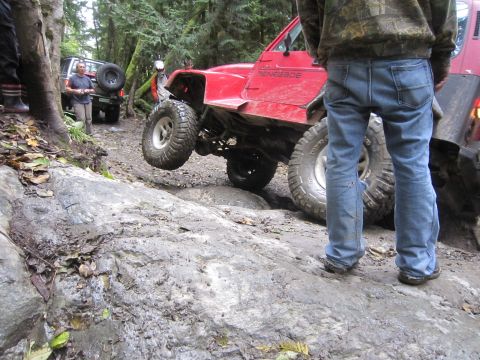 2008 Jeep Wrangler - A red Jeep Renegade navigates a challenging rocky trail, with another vehicle visible in the background.