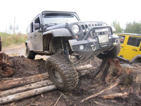 2008 Jeep Wrangler - A black 2008 Jeep Wrangler tackles a challenging off-road course, with another Jeep visible behind it.