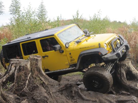 2008 Jeep Wrangler - A yellow 2008 Jeep Wrangler Rubicon navigates an obstacle course of large tree stumps.