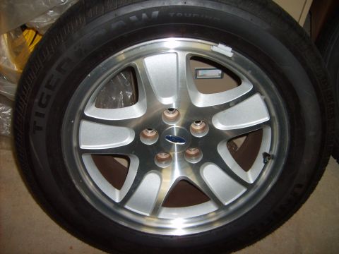 1993 Ford Crown Victoria - A silver 5-spoke wheel with a blue Ford logo is shown close up.