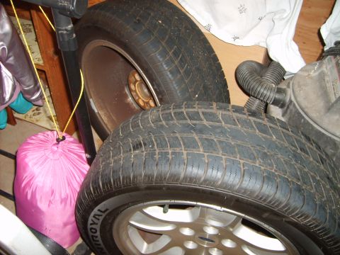 1993 Ford Crown Victoria - Close-up view of two tires and wheels, one with a silver alloy rim and the other with a rusty steel rim.