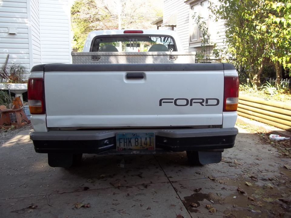 Rear view of white Ford pickup truck with a toolbox in the bed