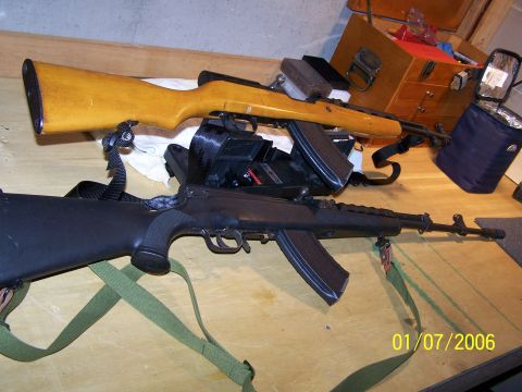 1989 Ford Bronco - Two rifles are displayed on a wooden table with a chest and bag in the background.
