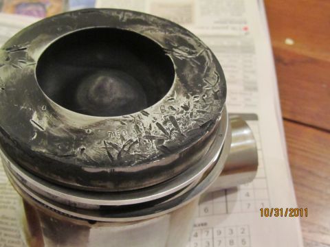 1984 Ford Bronco - Close-up of a damaged engine piston, showing wear and part number markings.