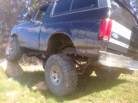 1995 Ford Bronco - This 1992 Ford Bronco is shown navigating rough terrain, with its tires on rocks and mud covering its exterior.