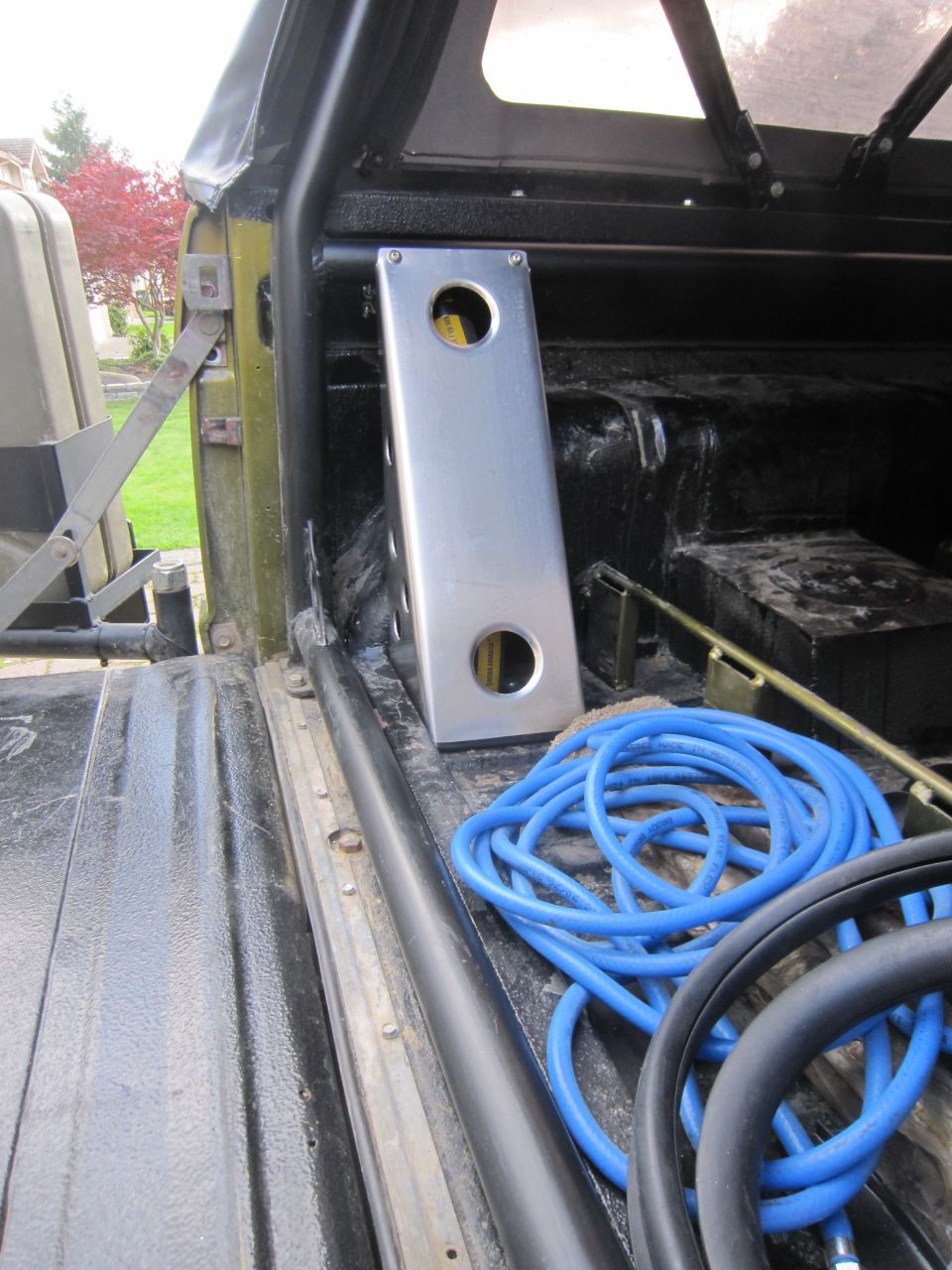 Interior cargo area of a vehicle showing a rolled blue hose and a metal bracket