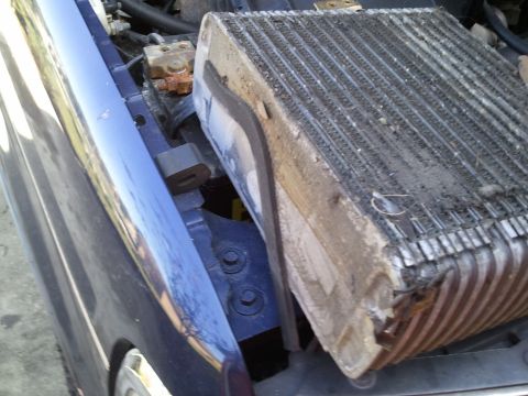 1994 Ford Bronco - The AC evaporator core is shown removed from the vehicle's engine bay, revealing its dirty and damaged condition.