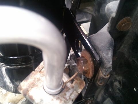 1994 Ford Bronco - Close-up view of a metal pipe and bracket, likely part of a vehicle's AC system, showing signs of rust on a bolt.