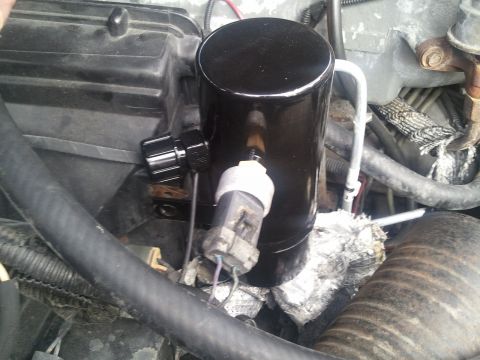 1994 Ford Bronco - Close-up of an AC accumulator, a component in a vehicle's air conditioning system.