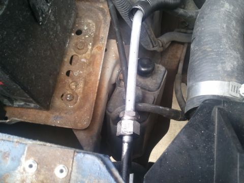 1994 Ford Bronco - Close-up view of engine bay components, including a rusty bracket and hoses, with visible website text.