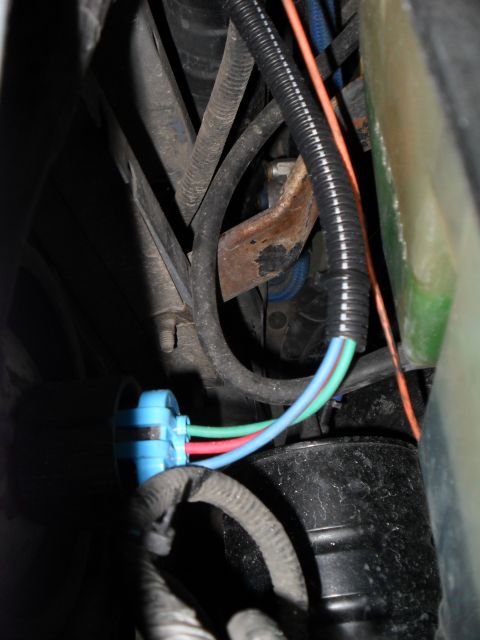 1990 Ford Bronco - Close-up of a blue headlight harness connector with three colored wires visible.