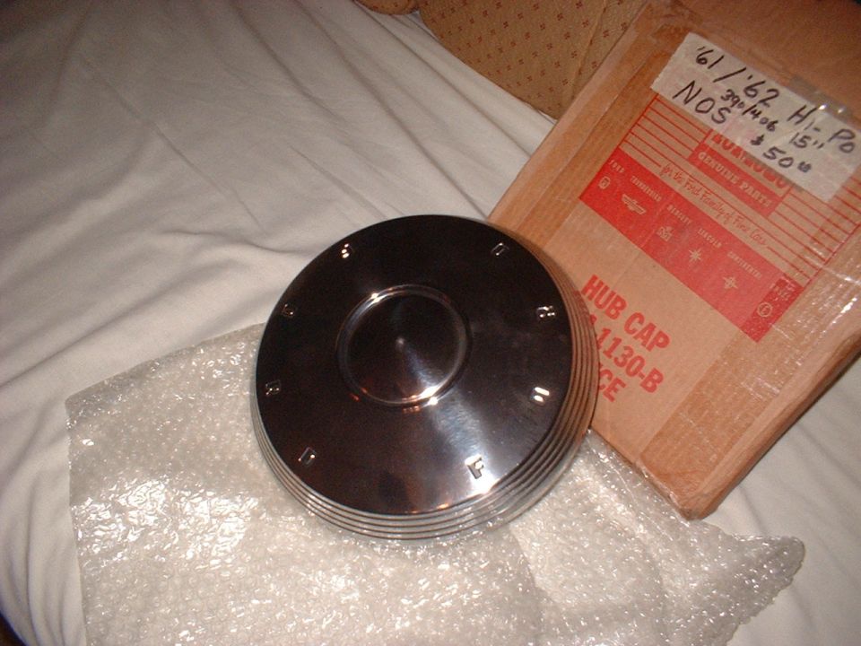 Chrome hub cap with embossed letters, next to a cardboard box labeled 'HUB CAP 1130-B'
