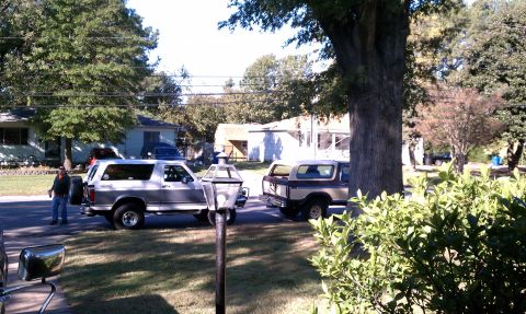 1979 Ford Bronco - Two Ford Broncos, one a 1979 model, are parked on a street in front of houses.