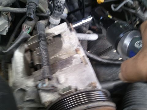 1994 Ford Bronco - Close-up view of an engine component, possibly an AC compressor, with a pulley and wiring harness visible.