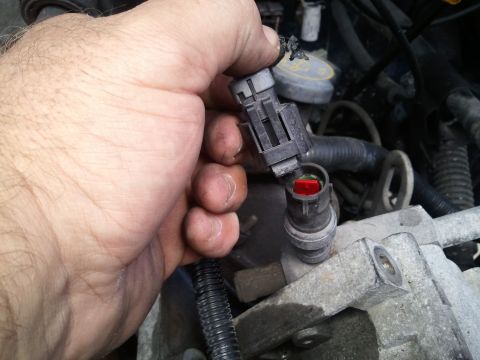 1994 Ford Bronco - Disconnecting an electrical connector from an engine component, likely for AC system maintenance.