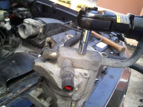 1994 Ford Bronco - Removing the AC compressor from an engine bay with a socket wrench.