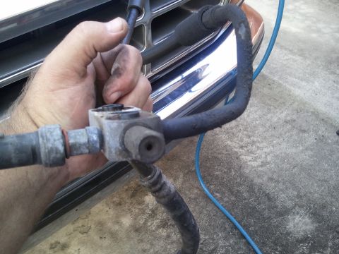 1994 Ford Bronco - Close-up of a vehicle's AC hose assembly being held by a hand, with a chrome grille in the background.