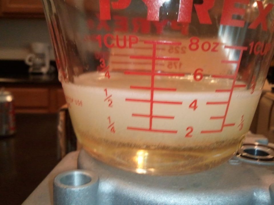 Measuring cup with liquid, showing markings for cups, ounces, and milliliters. Some sediment at the bottom