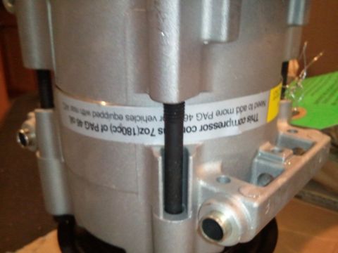 1994 Ford Bronco - AC compressor part with label detailing oil capacity and R134a system requirements.