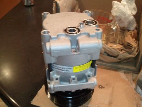 1994 Ford Bronco - An air conditioning compressor is shown, likely a replacement part, with visible text on a yellow label.