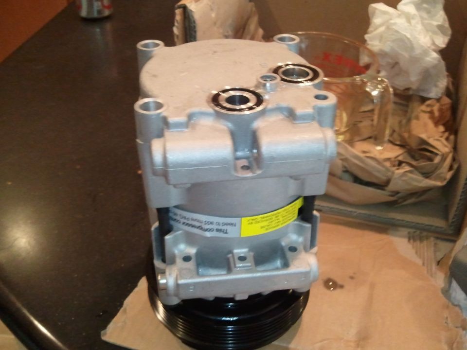 Silver air conditioning compressor with yellow label and black pulley