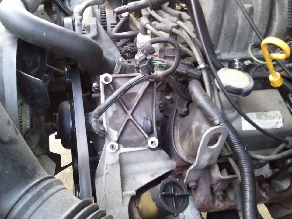 Close-up of engine bay with hoses, wires, and belts visible