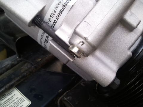 1994 Ford Bronco - A close-up view of an AC compressor, showing a bolt and a label with part information.