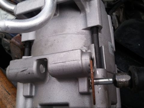 1994 Ford Bronco - AC compressor part shown in detail, with attached metal lines and a tool nearby.