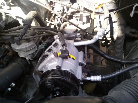1994 Ford Bronco - Close-up of the AC compressor and associated hoses within the engine bay of a 1994 Ford Bronco.