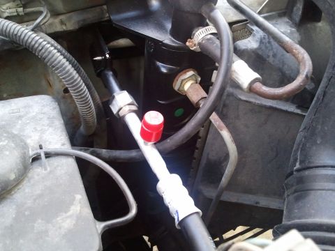 1994 Ford Bronco - Close-up view of AC system components, including hoses and a compressor.