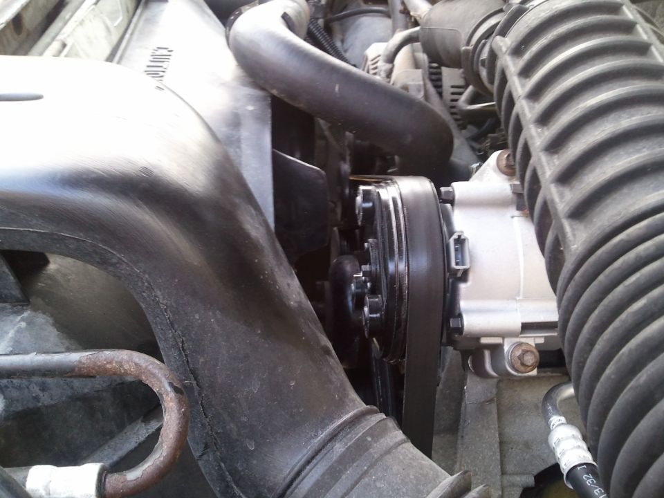 Engine bay AC compressor with belt and fan visible