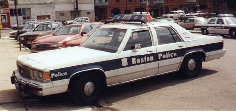 1991 Ford LTD Crown Victoria - white-and-blue Boston Police Ford LTD Crown Victoria sedan parked at a curb in front of a lot of other police cruisers.