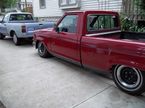 1970 Ford Ranchero - Two pickup trucks are parked on a concrete driveway in front of a house.