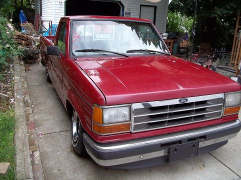 1970 Ford Ranchero - A red Ford pickup truck is parked in a driveway with a "For Sale" sign visible through the windshield.